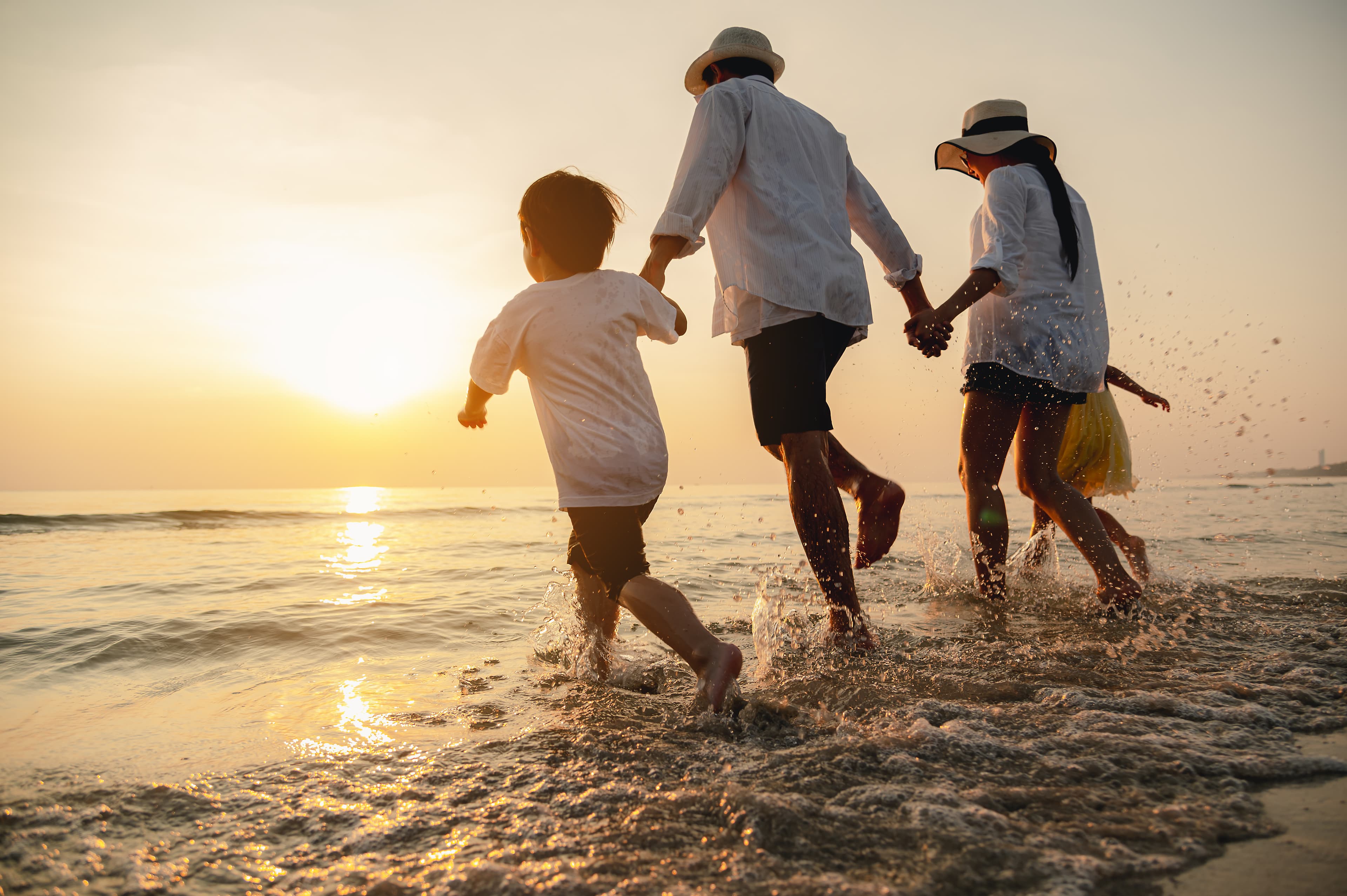 Family running through the surf at sunset